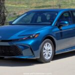 **Alt Text:** Toyota Camry LE 2025 – elegant silver sedan with sleek LED headlights and stylish body lines, parked in a modern urban setting.