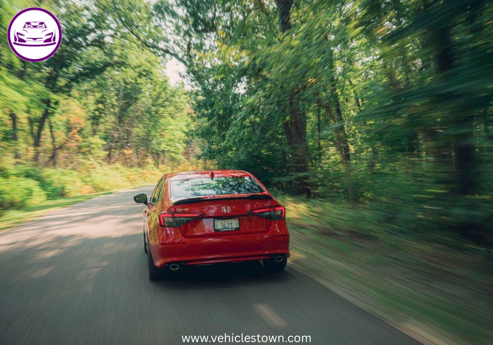 Honda Civic Si sporty red sedan parked, showcasing aggressive front grille and alloy wheels.
