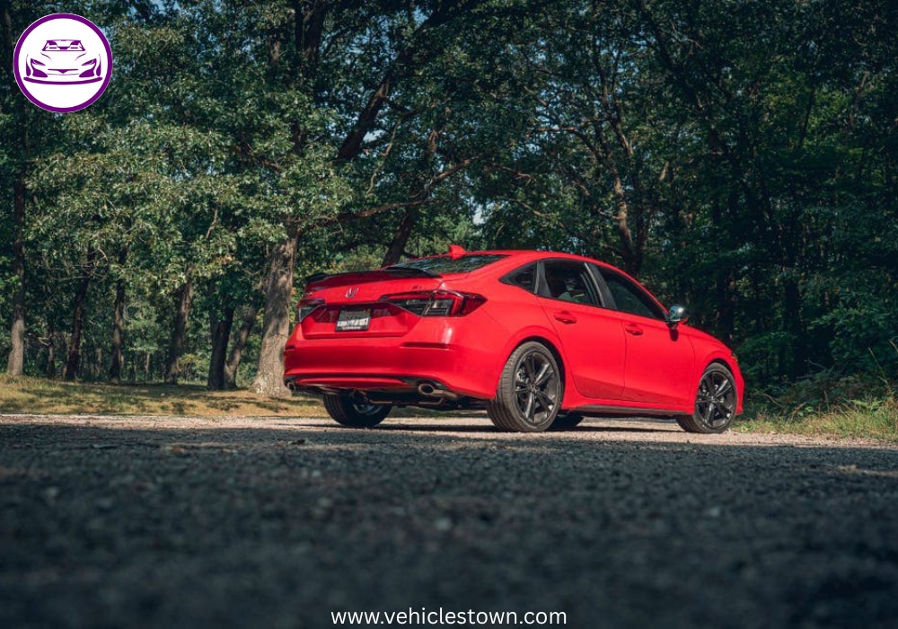 Honda Civic Si sporty red sedan parked, showcasing aggressive front grille and alloy wheels.