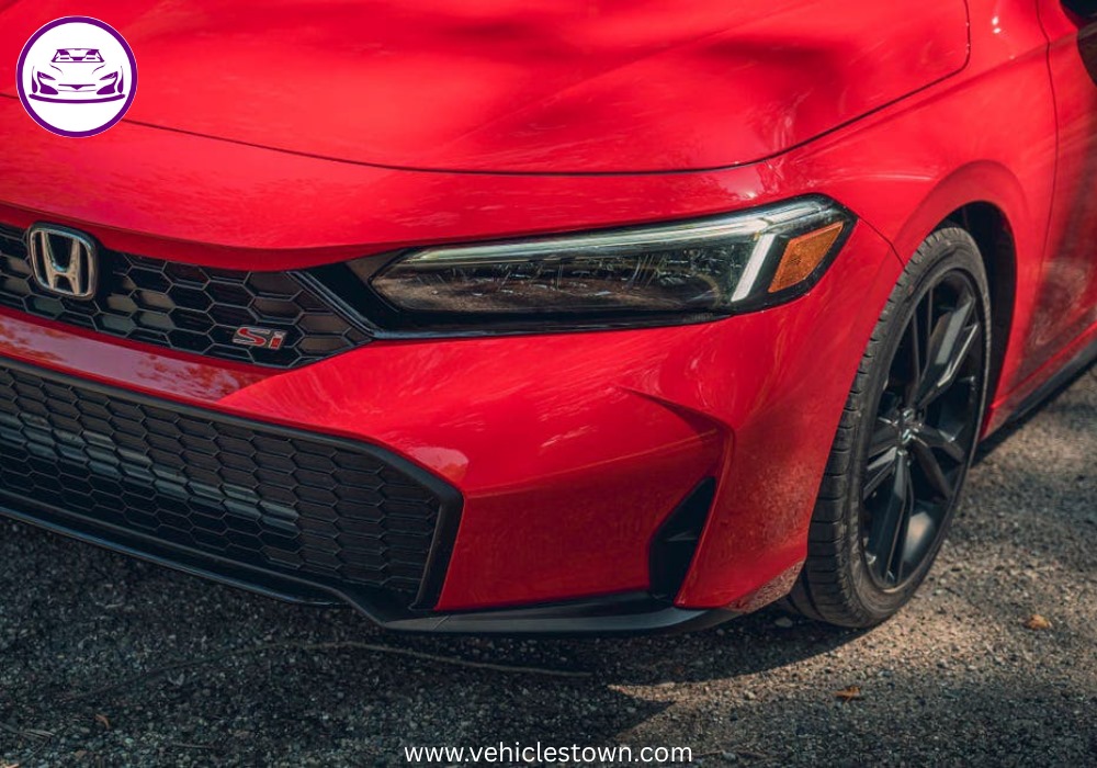 Honda Civic Si sporty red sedan parked, showcasing aggressive front grille and alloy wheels.