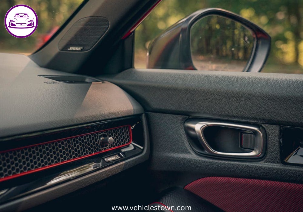 Honda Civic Si sporty red sedan parked, showcasing aggressive front grille and alloy wheels.