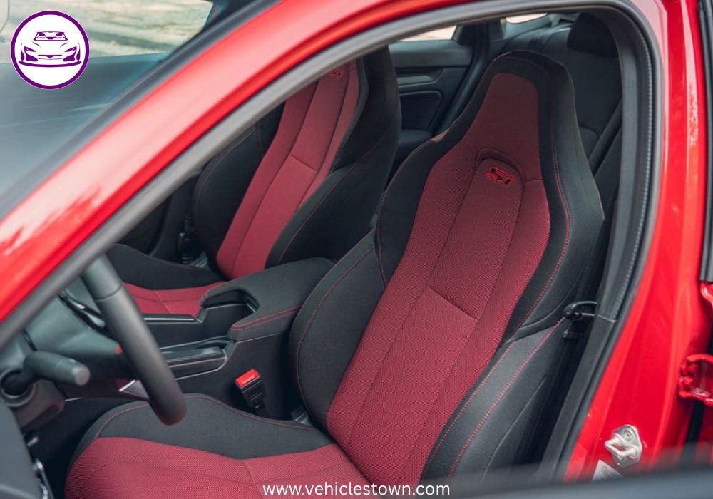 Honda Civic Si sporty red sedan parked, showcasing aggressive front grille and alloy wheels.