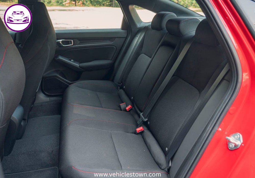 Honda Civic Si sporty red sedan parked, showcasing aggressive front grille and alloy wheels.