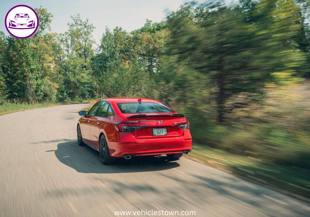 Honda Civic Si sporty red sedan parked, showcasing aggressive front grille and alloy wheels.