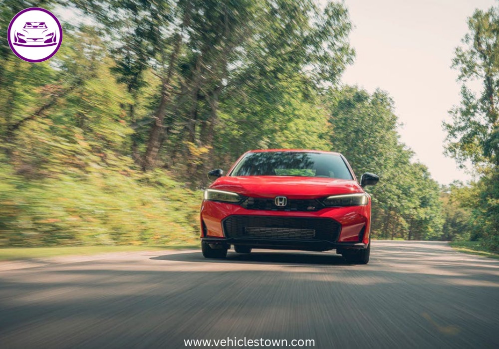 Honda Civic Si sporty red sedan parked, showcasing aggressive front grille and alloy wheels.